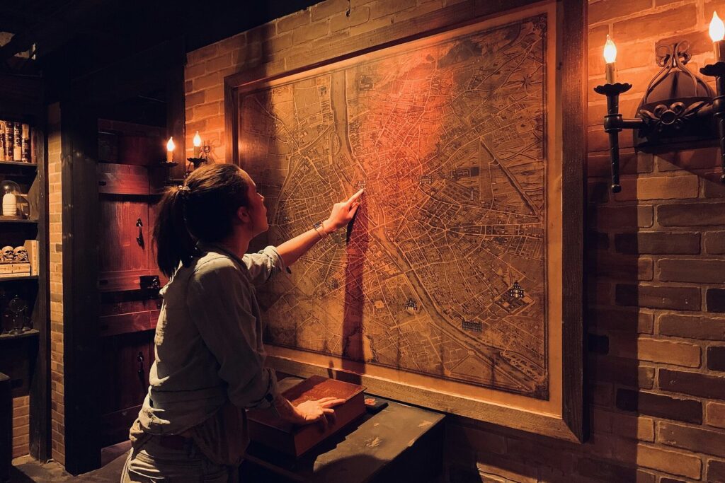 Person untersucht in einem stimmungsvoll beleuchteten Escape Room eine große Karte an der Wand