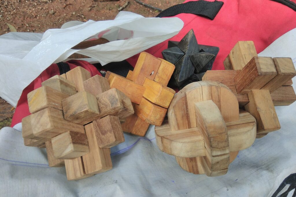 Verschiedene Holz-Knobelspiele aus ineinander verzahnten Stäben auf einem Tuch