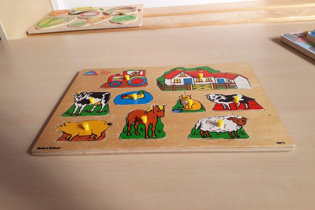 Holz-Steckpuzzle mit bunten Bauernhoftieren auf einem Tisch
