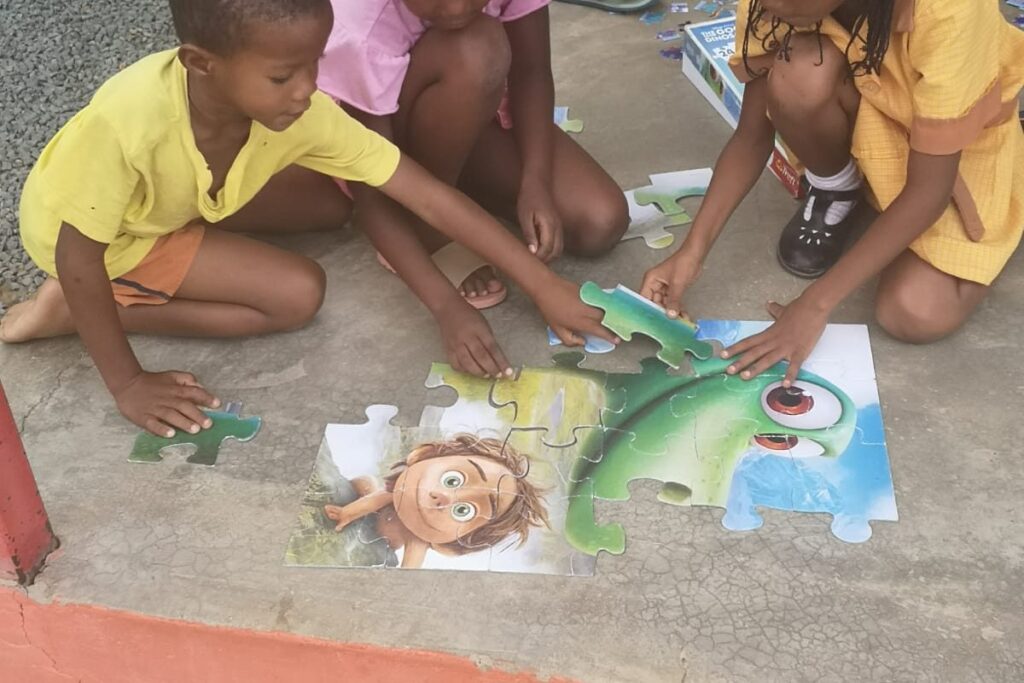 Mehrere Kinder sitzen auf dem Boden und setzen gemeinsam ein buntes Puzzle zusammen