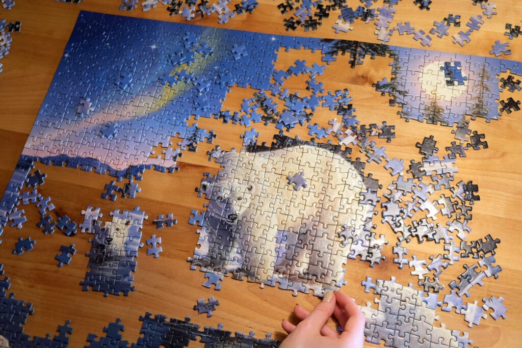 Halb fertiges Puzzle mit Eisbär-Motiv auf einem Holztisch, daneben lose Teile