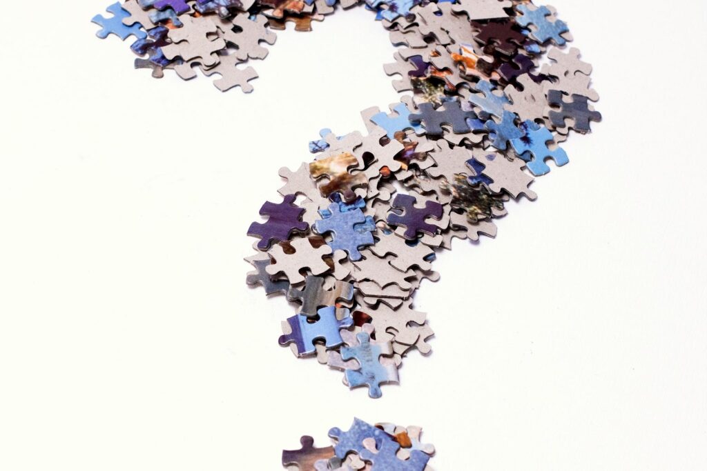 Fragezeichen aus bunten Puzzleteilen auf weißem Hintergrund