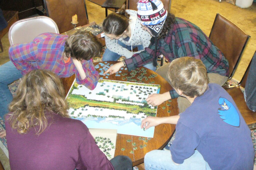 Mehrere Menschen puzzeln gemeinsam an einem runden Tisch