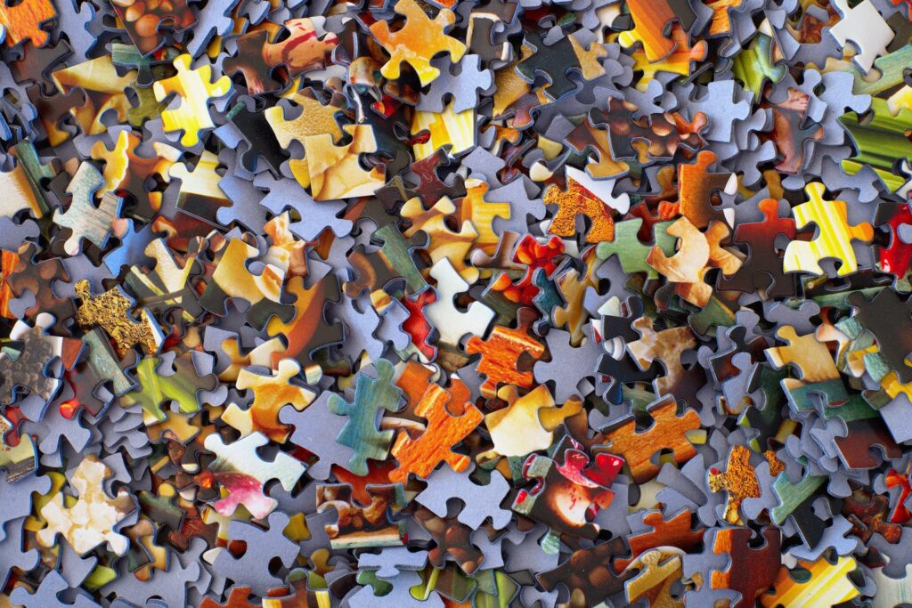 Viele bunte Puzzleteile liegen durcheinander auf einem Tisch